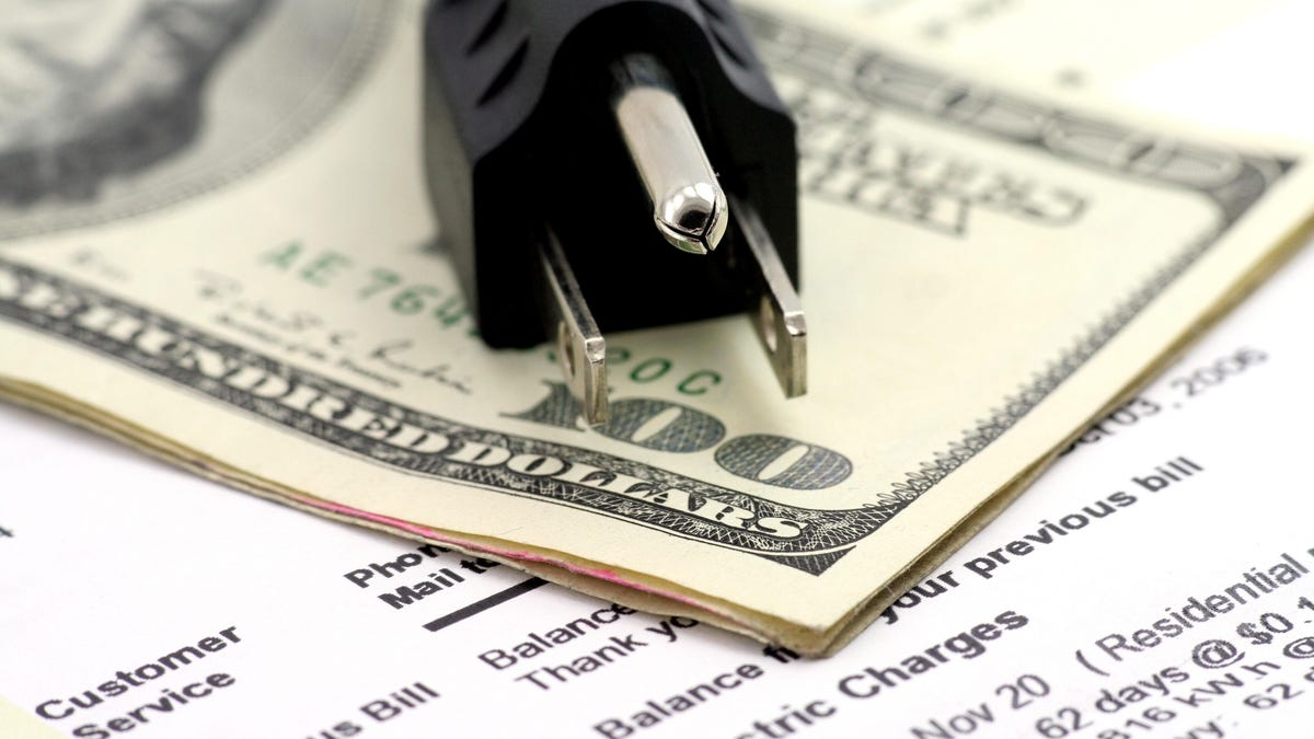 An electric plug sitting on top of cash and an energy bill