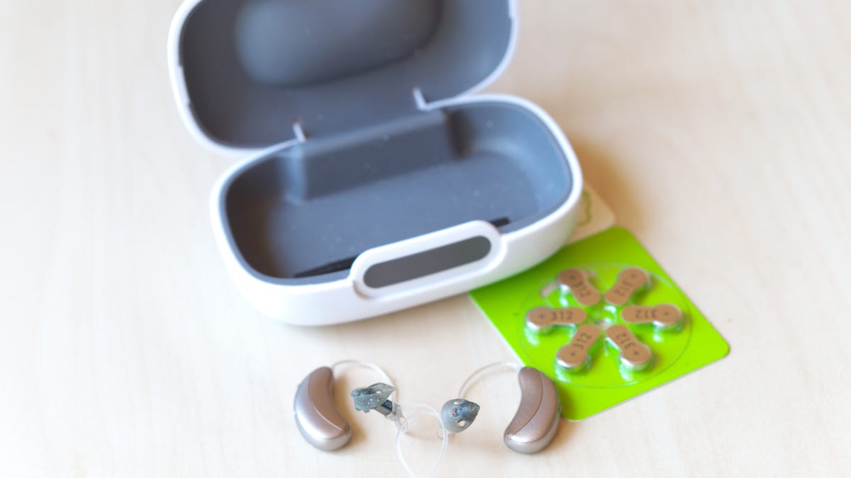 A pair of hearing aids with case and extra batteries.