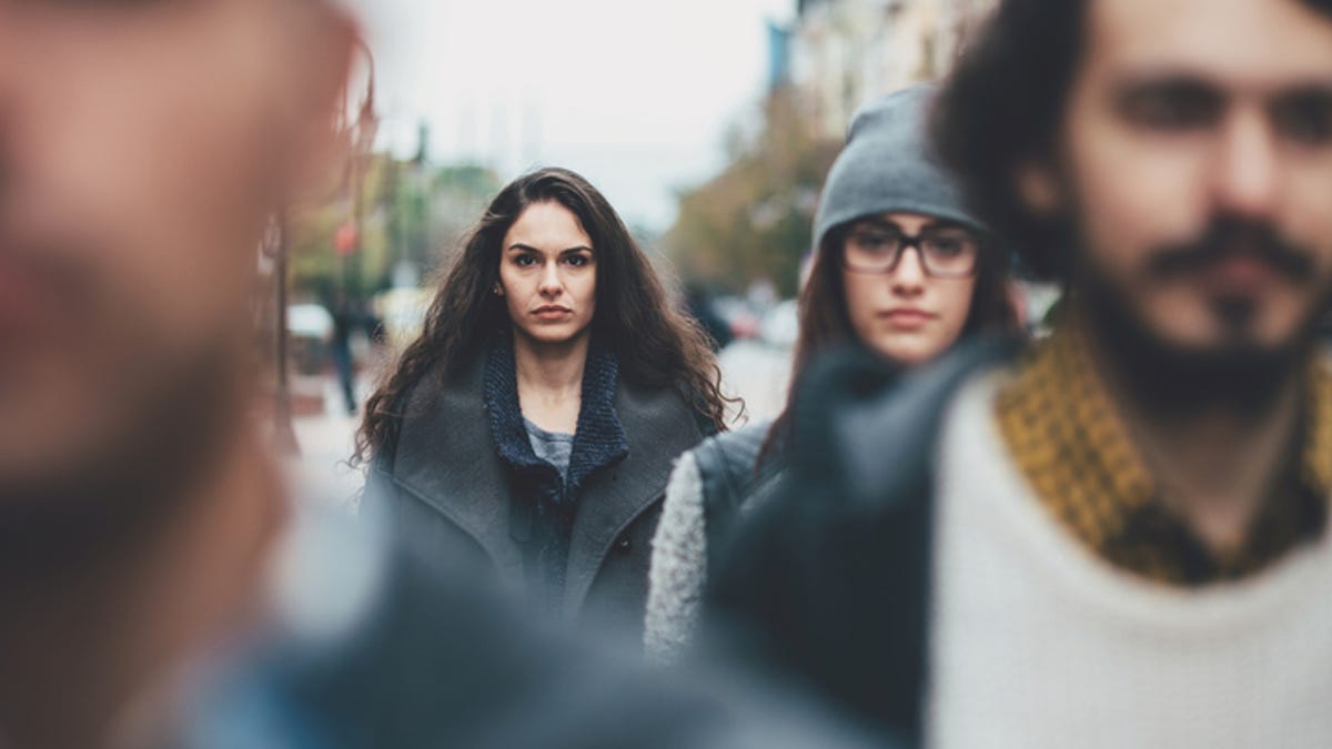 A woman walking on the street with a crowd in front of her.