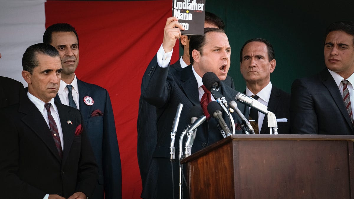 Giovanni Ribisi as Joe Colombo holding up a copy of the book The Godfather