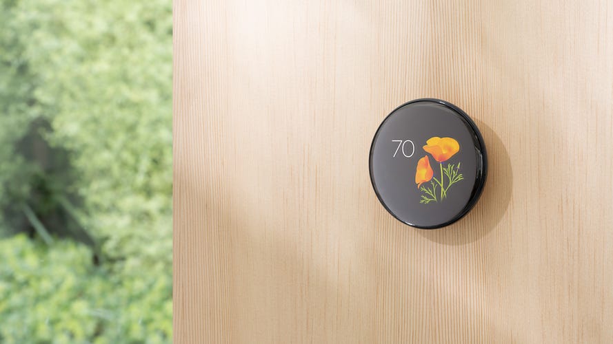 A Nest thermostat on a wall shows a poppy animation.