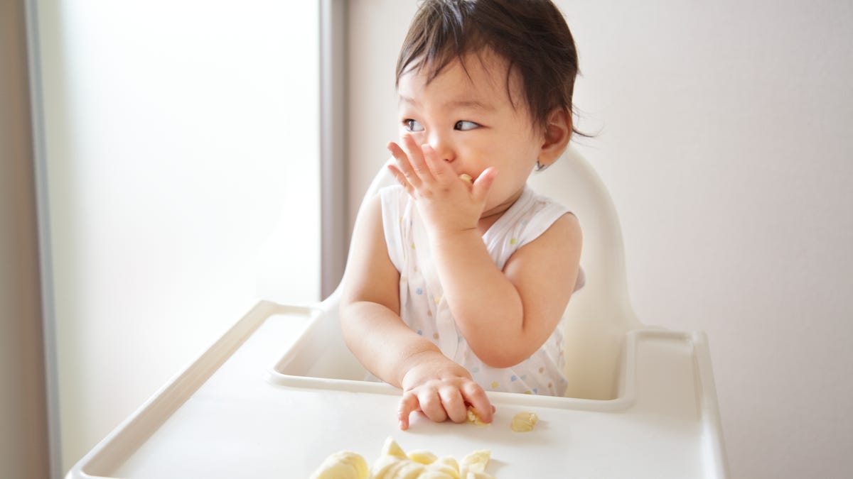 Baby eating bananas in high chair