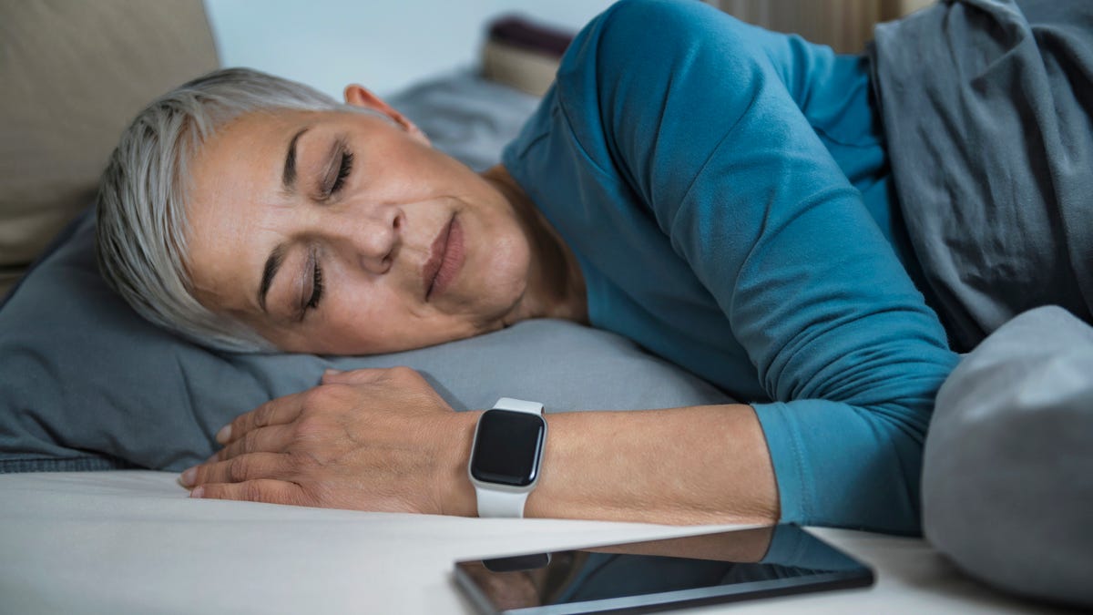 A woman sleeping with a sleep tracker on her wrist.
