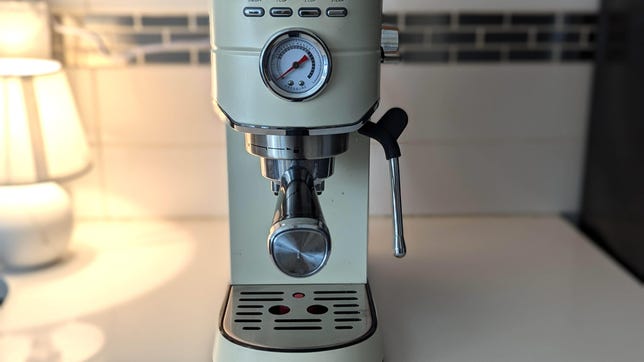 a small espresso machine on a kitchen counter with a lamp next to it