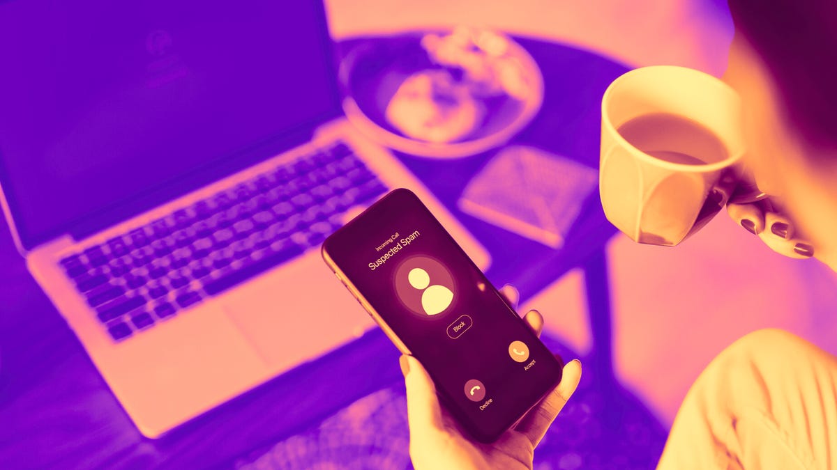 A woman looks at her phone, displaying a "potential spam" caller ID.