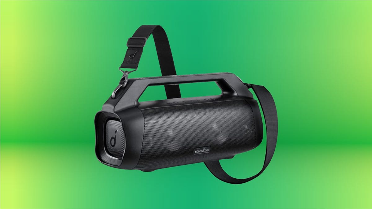 Black portable speaker with carrying strap on a green background