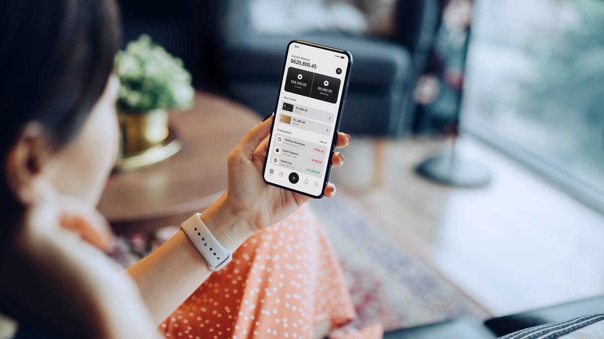 A woman holds a smartphone showing investment information