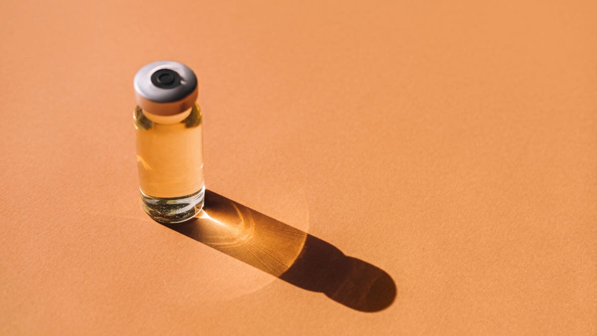 A vial of medication against an orange background