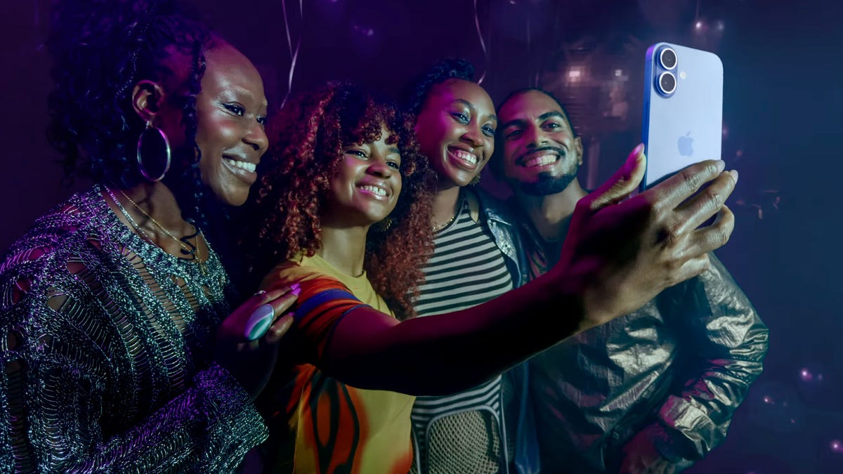 Four people post for a selfie using an iPhone.