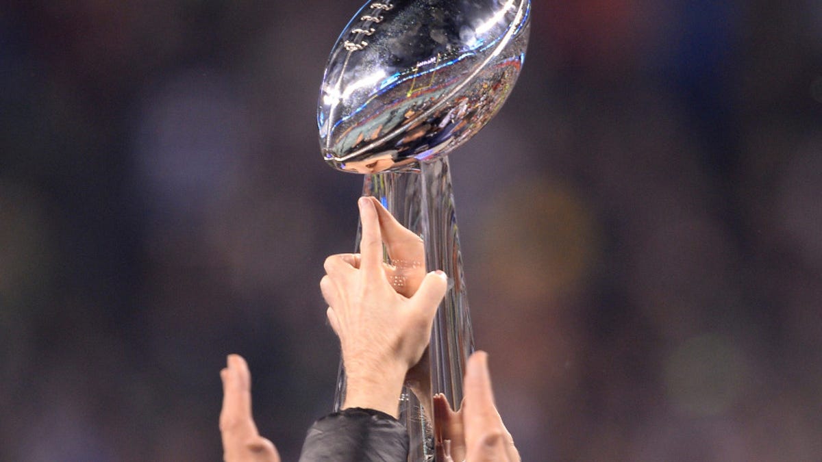 Hands raising the Super Bowl trophy.