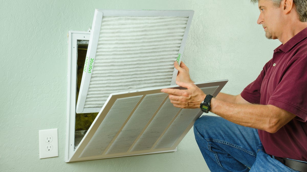 Home owner putting new air filter on air conditioner