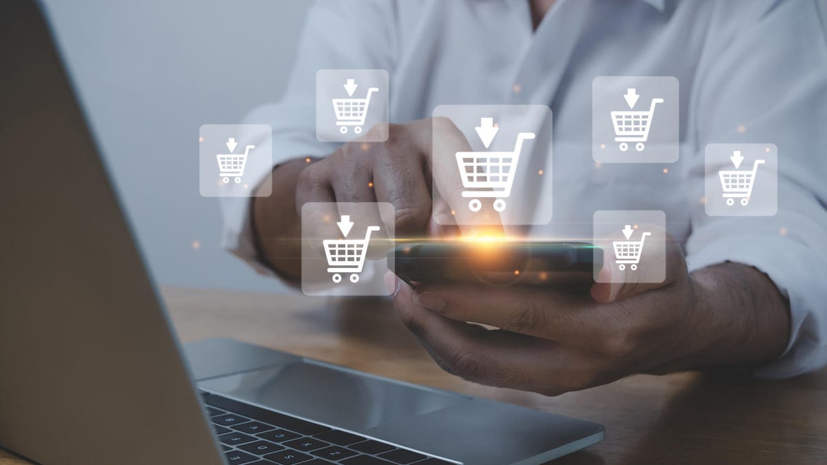 Hands holding a mobile phone surrounded by pop-up bubbles showing shopping carts