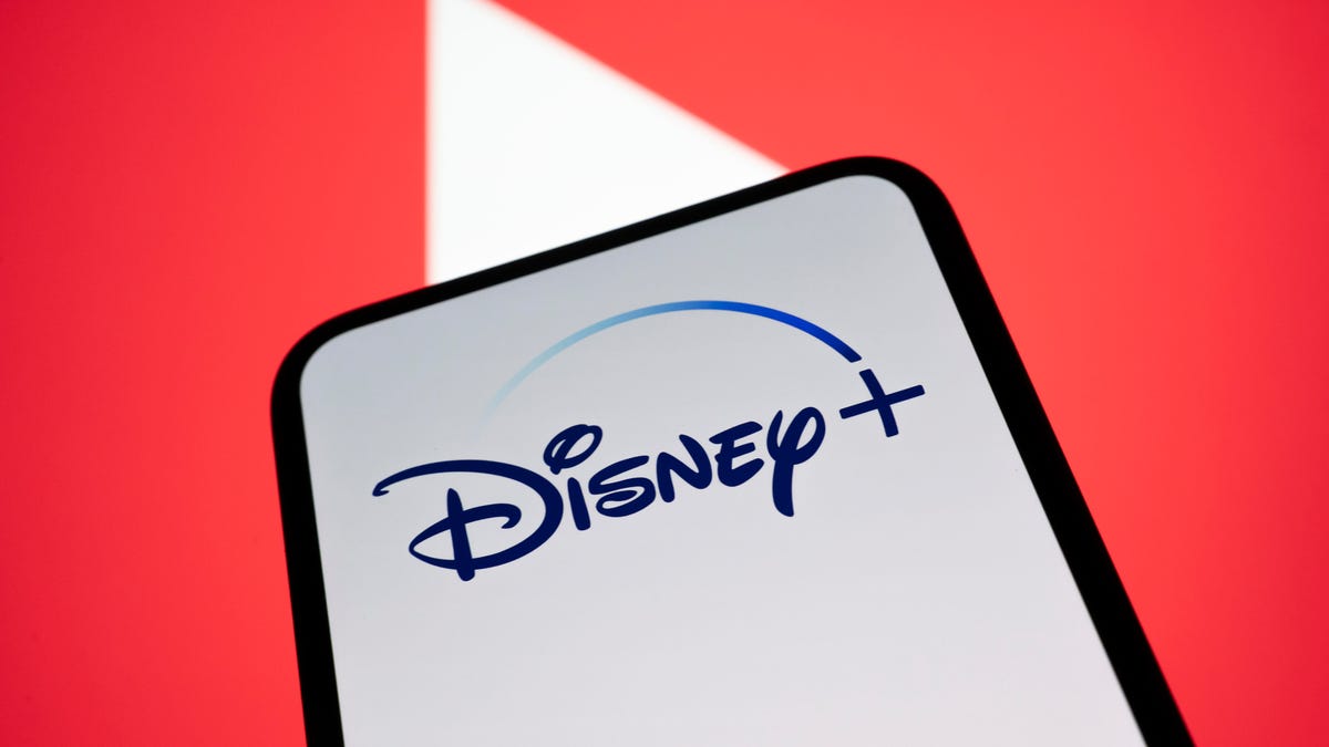 the Disney Plus logo on a mobile phone in front of the YouTube logo