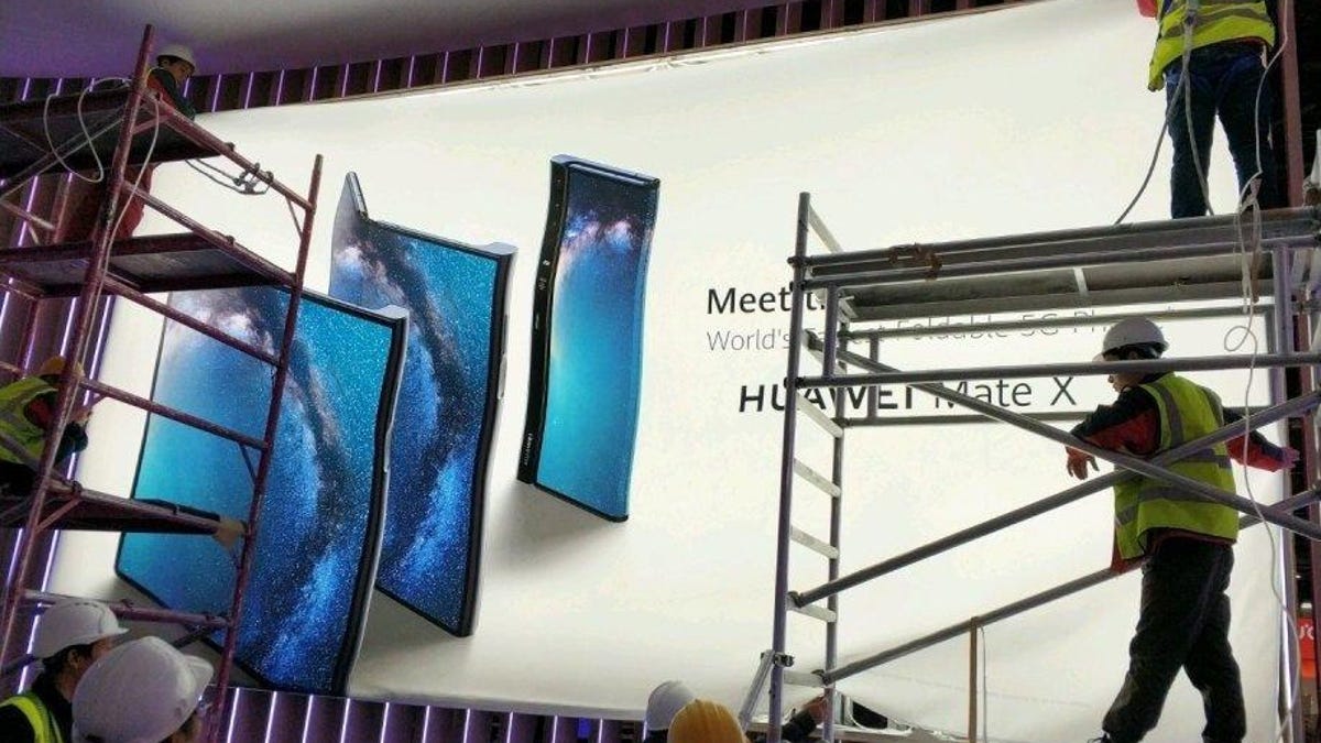 Workers putting up a billboard that purportedly shows Huawei's Mate X foldable phone.