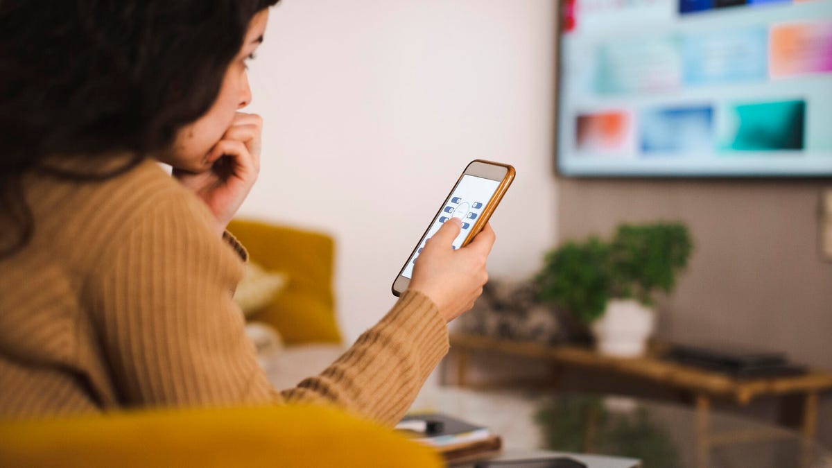 woman-watching-tv-with-phone-gettyimages-1400704519