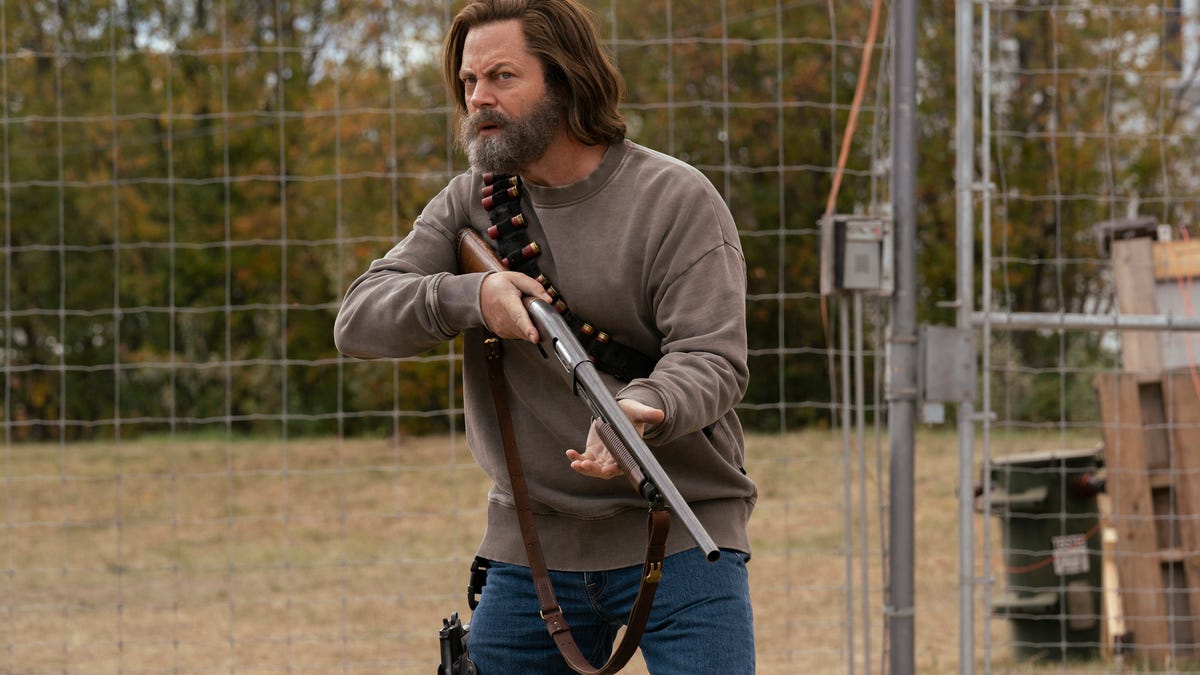 Nick Offerman's Bill wields a shotgun while standing next to chain-link fence in The Last of Us episode 4