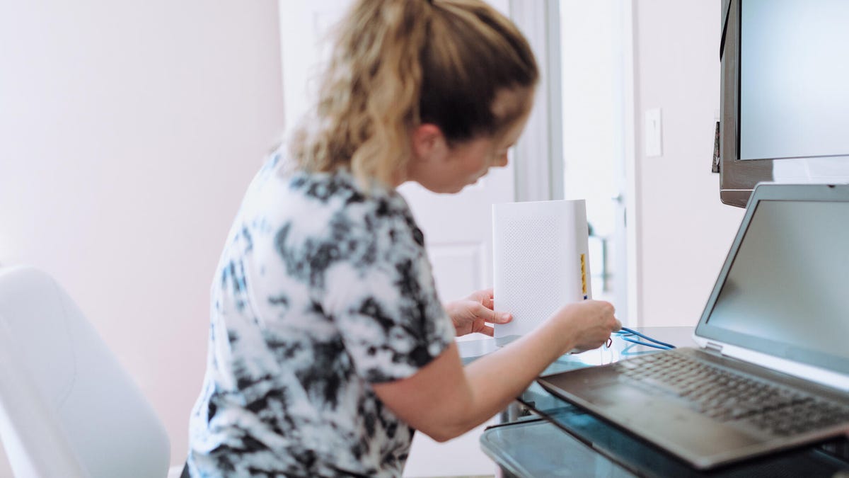 Woman rebooting internet router.
