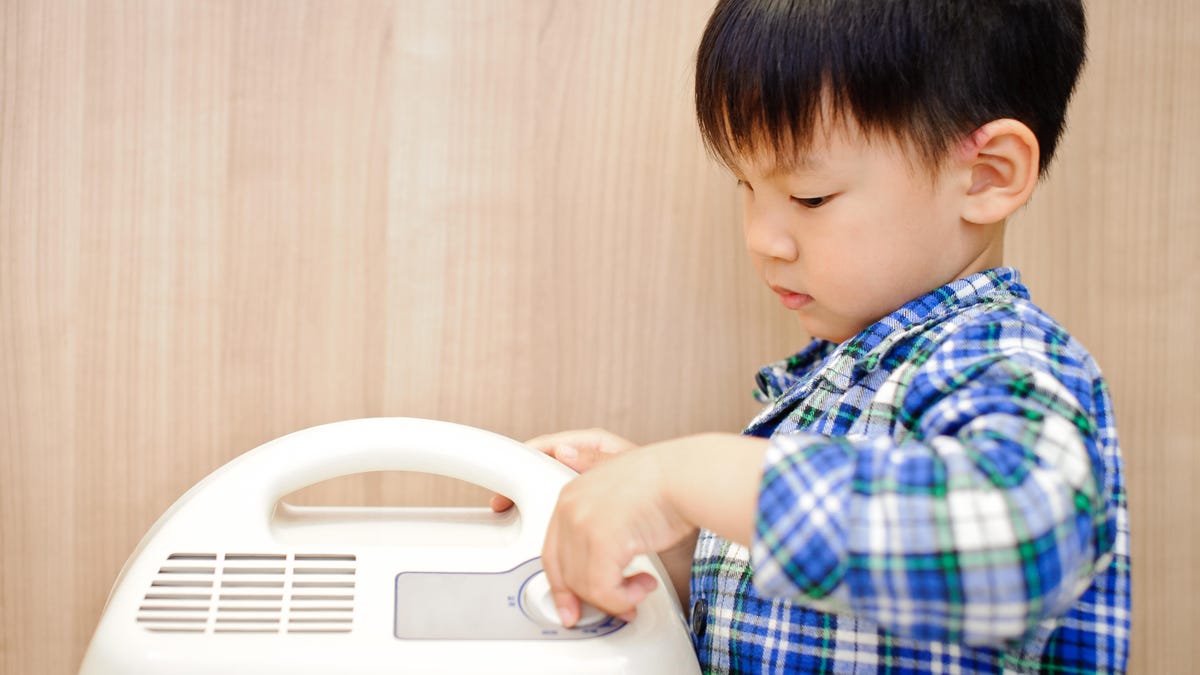 child adjusting a portable dehumidifier