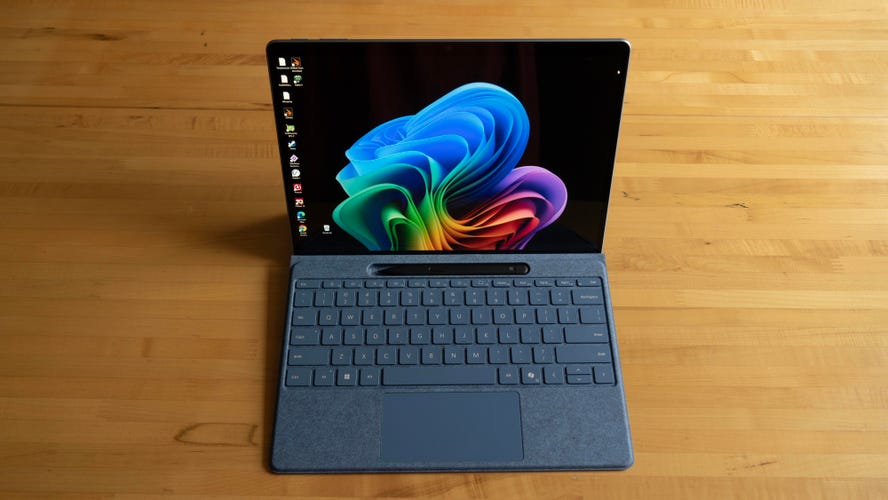 Microsoft Surface Pro 11 with Flex Keyboard and Slim Stylus sitting upright on a wood table