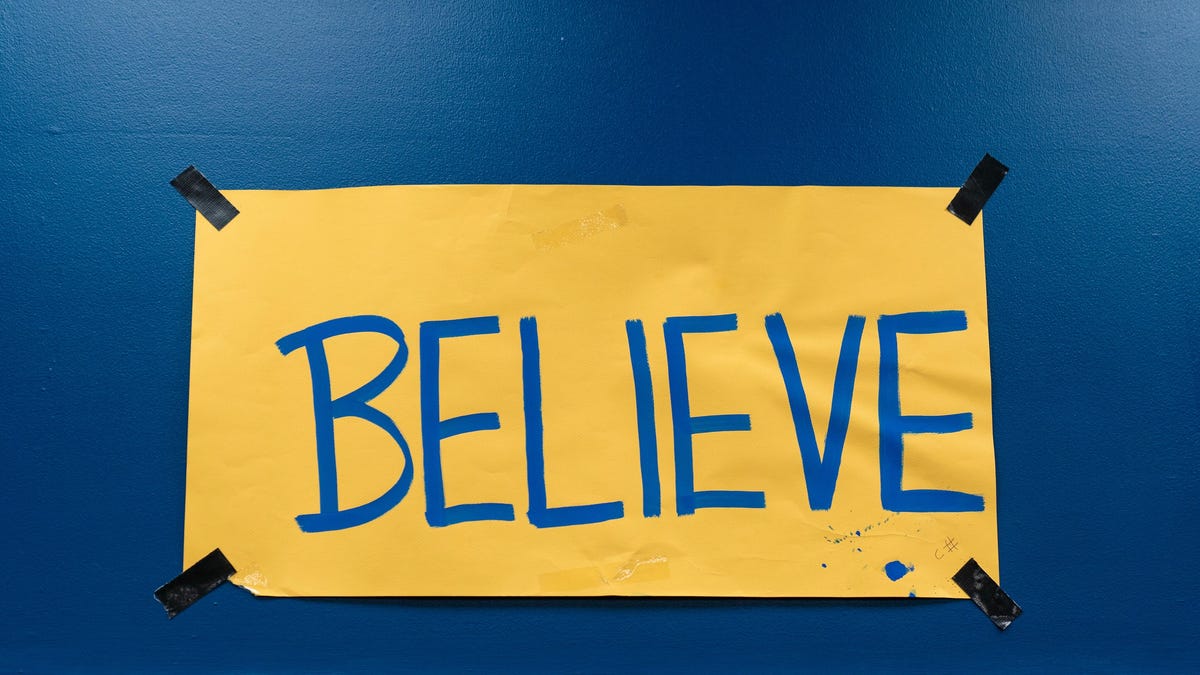 believe sign written on yellow paper on blue wall for Ted lasso