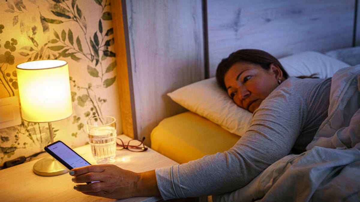 Woman checking her phone while lying in bed.