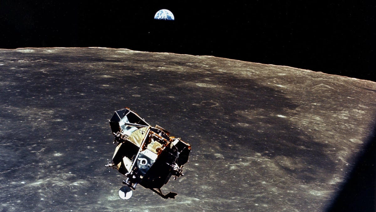 Apollo 11 lunar module in flight above the moon, with Earth in the background.