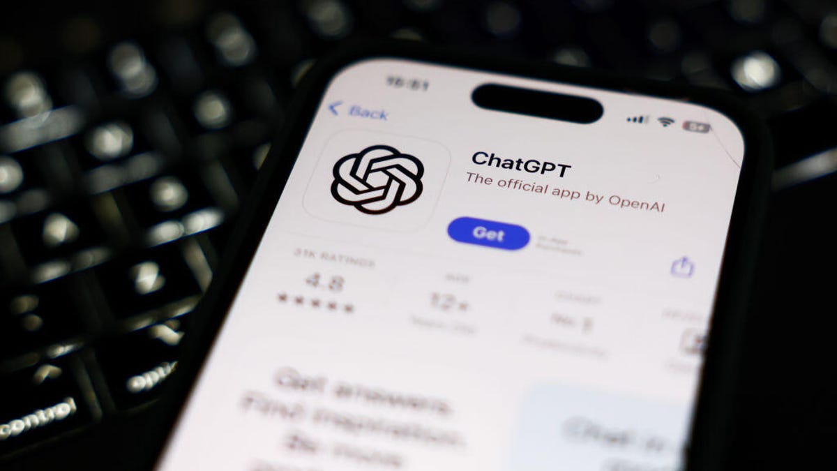 A phone with the ChatGPT app open in the App Store laying on top of a keyboard.