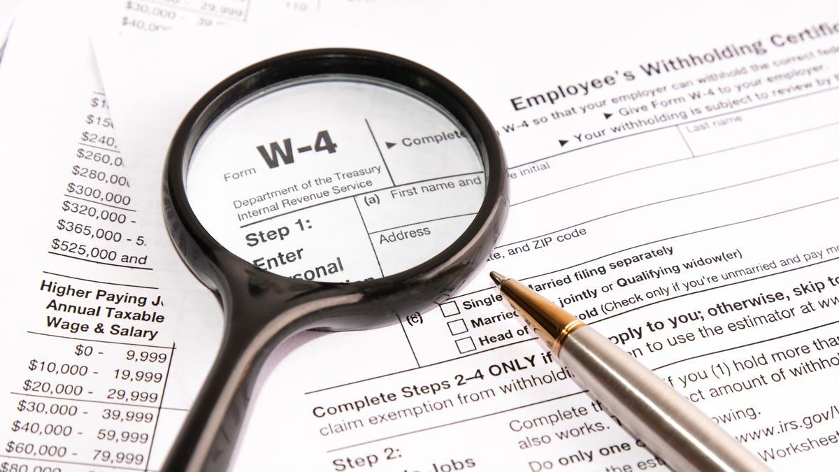 A magnifying glass and pen are placed on an IRS W-4 form
