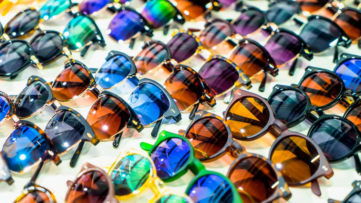 Rows of different sunglasses lying flat with different sunglass lens colors and frames.