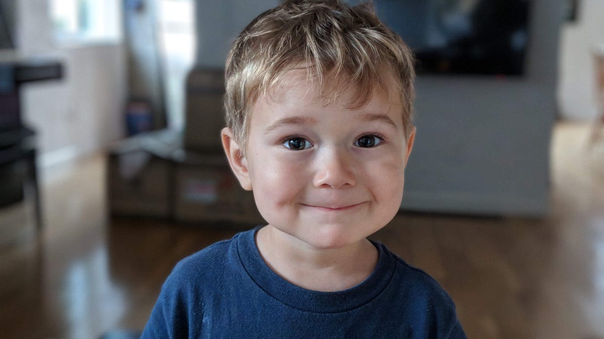 A photo of a smiling boy, the background behind him blurred artificially using computational photography methods