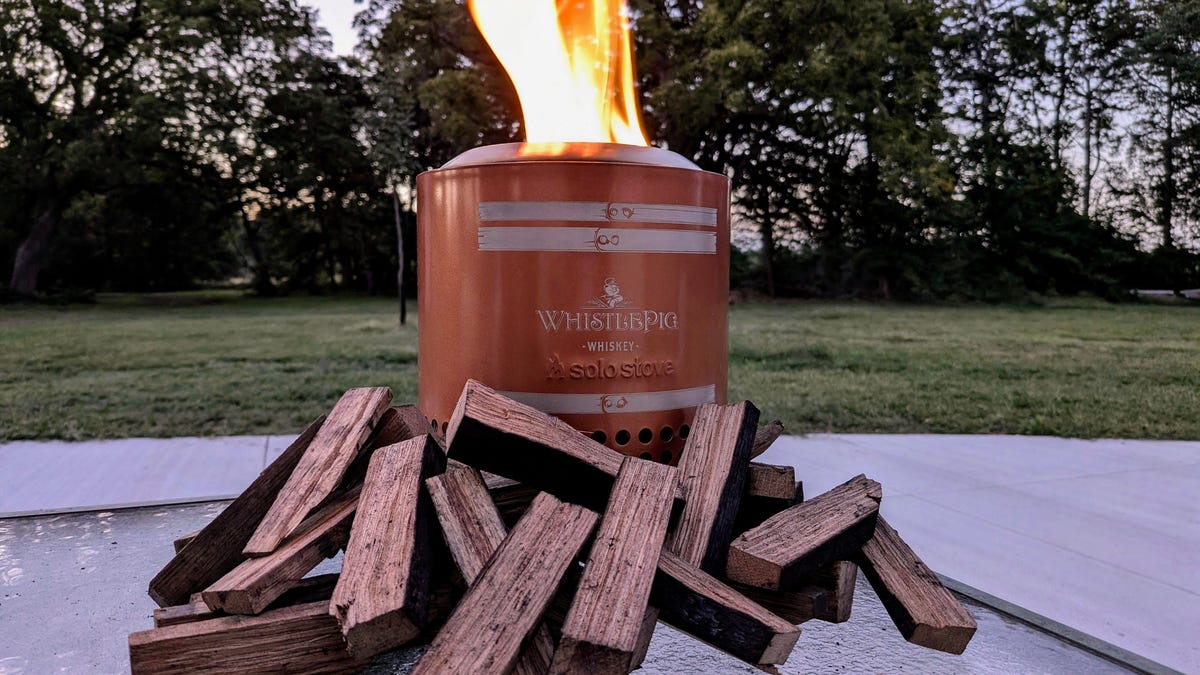 Solo Stove Mesa on a table with flames from the top with wood pieces surrounding the stove.