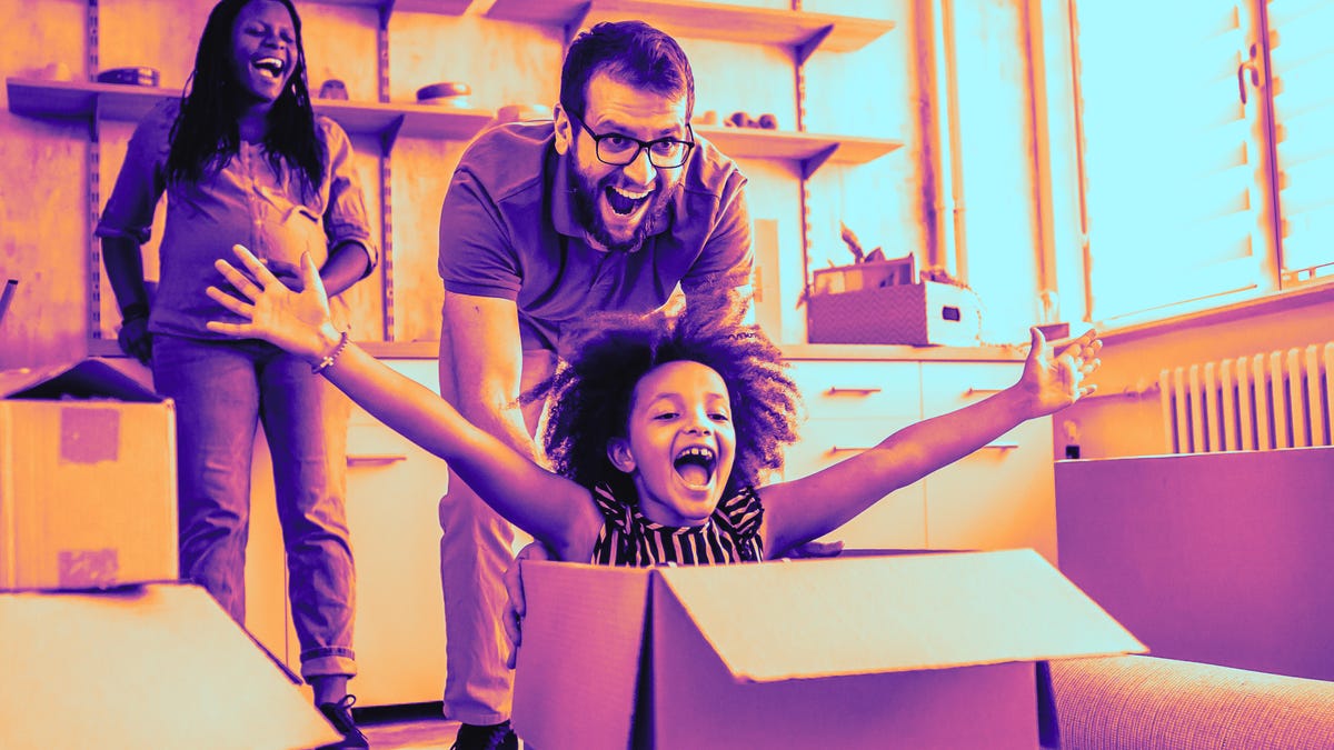 Father pushing daughter inside the box with mom laughing in the background