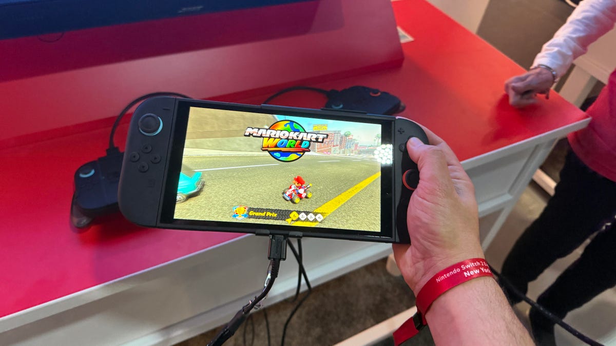 A hand holding the Nintendo Switch 2, with Mario Kart World on the screen