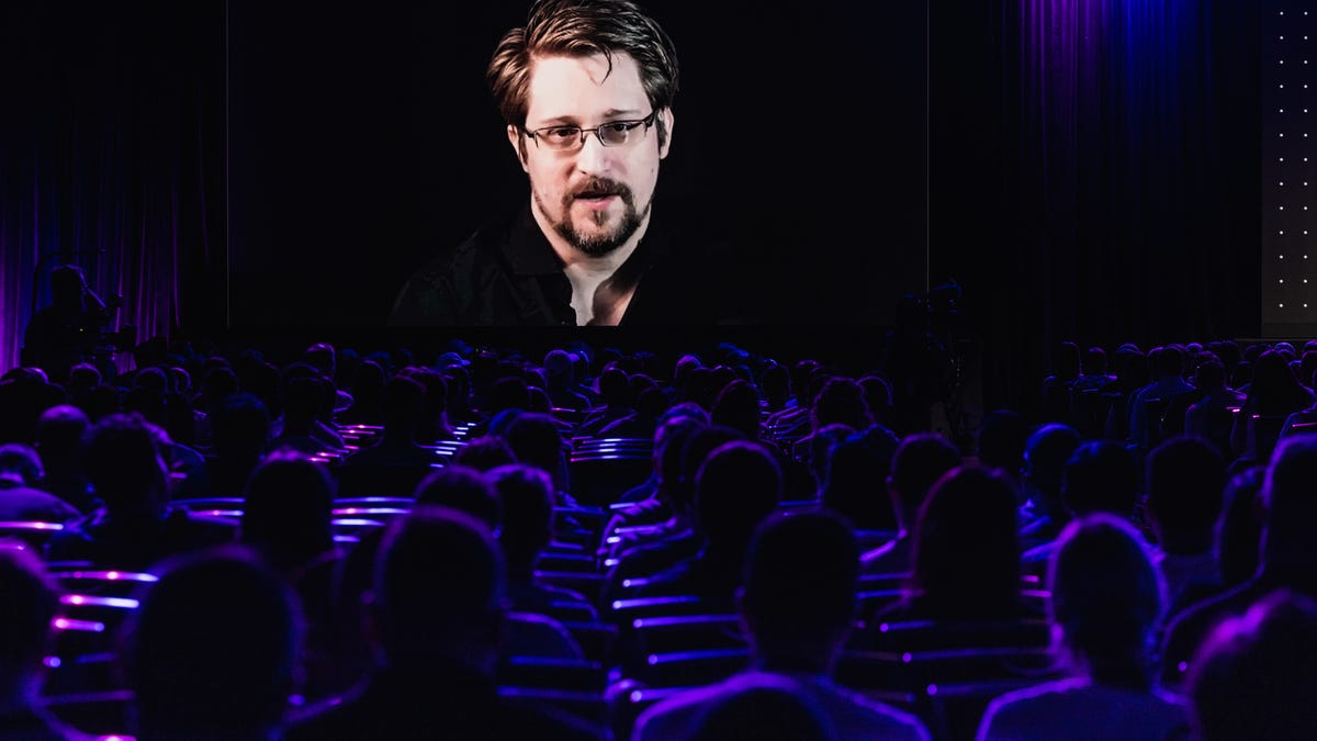 Edward Snowden speaking virtually on a big screen at a conference