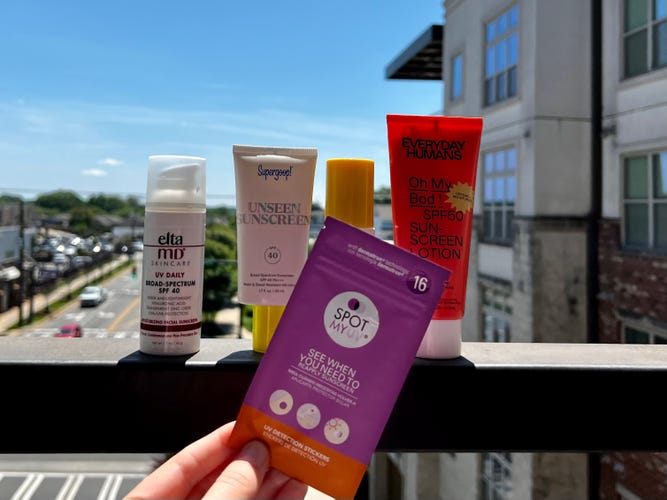 A package of UV Stickers in front of four different sunscreens