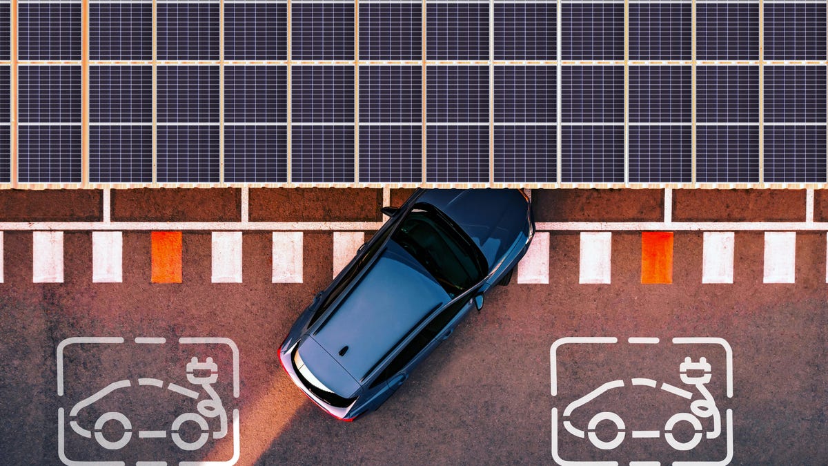 A car pulls under a canopy of solar panels.