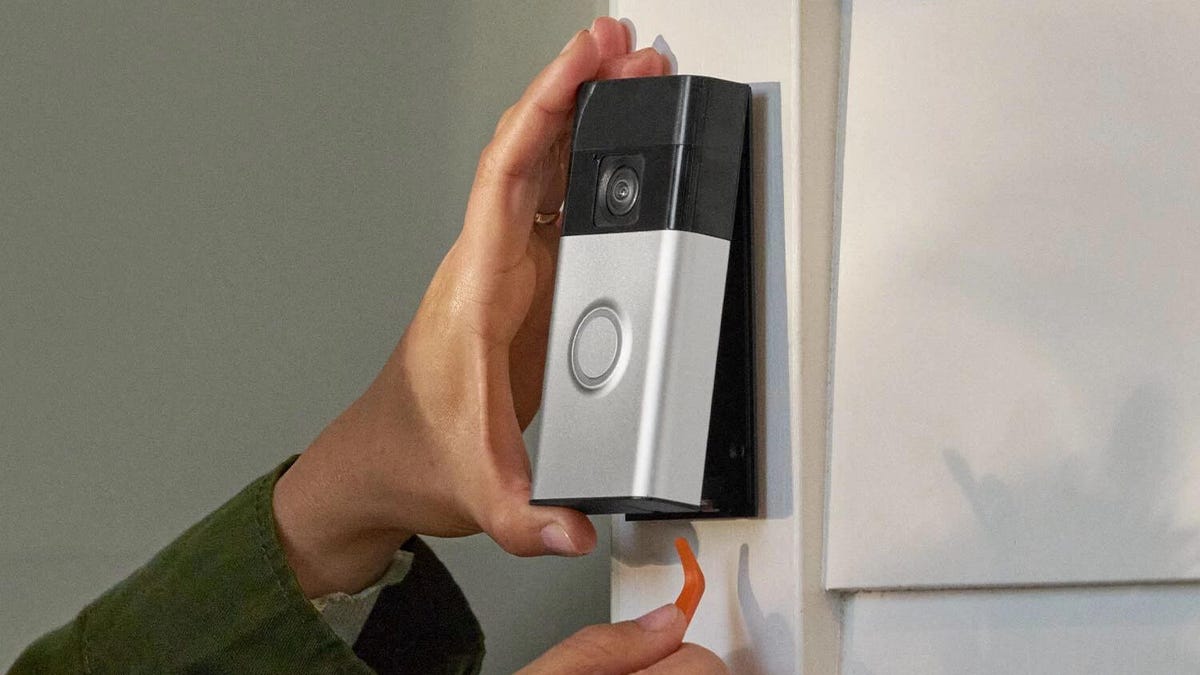 Hands use a push pin to snap off the new Ring Doorbell from its mount.