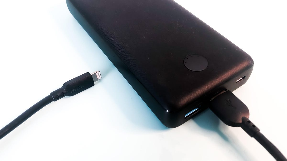 A rectangular black device with two USB-A ports. A phone charging cable is plugged in