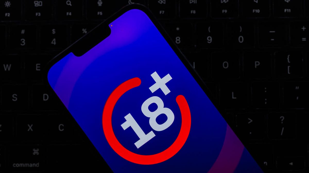 Age verification of 18+ is on a phone screen. The phone rests on a laptop keyboard.