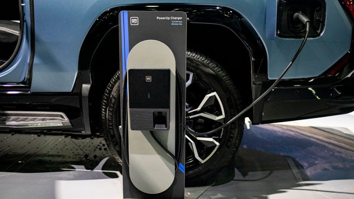 A GMC Sierra EV charges on a auto show floor.