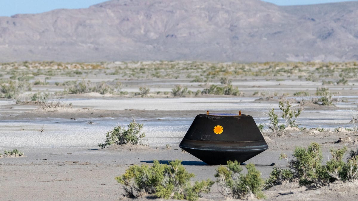 A black capsule, the size of a small appliance, sits on the ground in a Utah desert