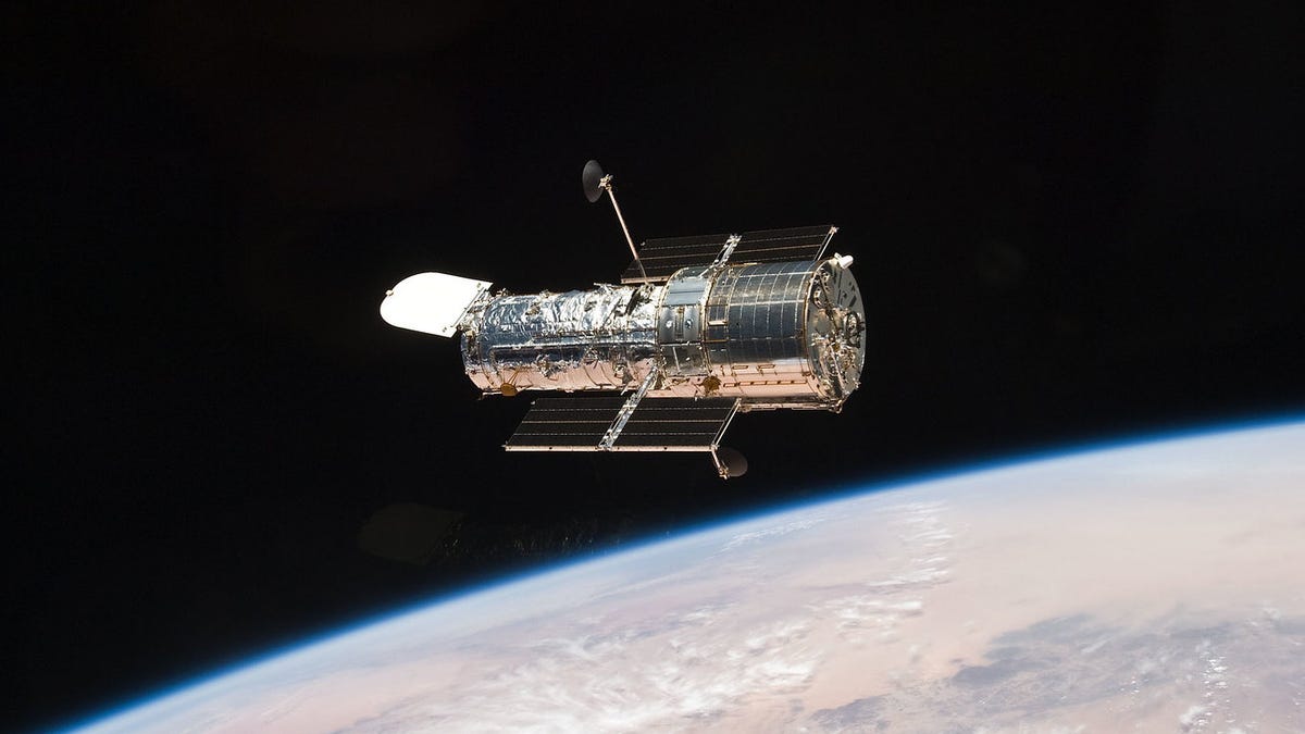 Hubble Space Telescope gleams against the darkness of space and the curve of the Earth.
