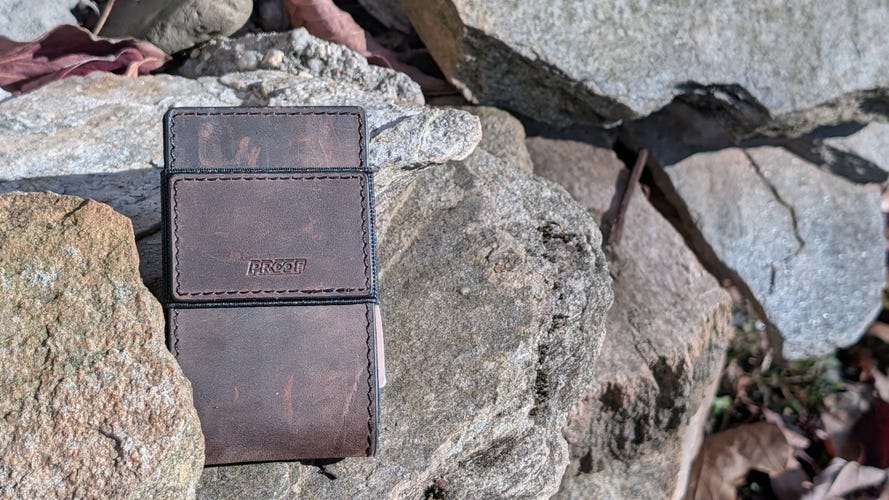 A brown leather wallet laying on some mossy slate