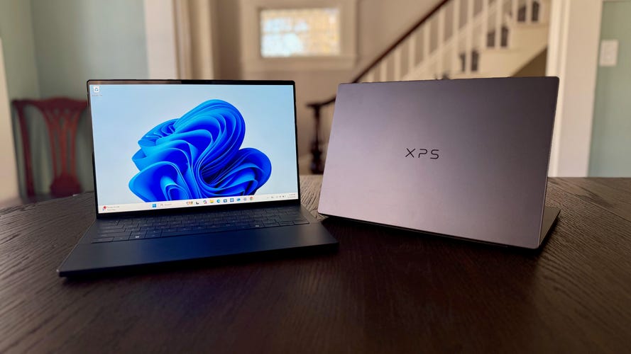 Dell XPS 14 laptops sitting front and back on a dining room table in front of a staircase