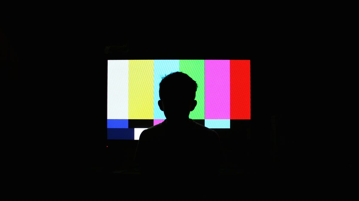 silhouette-of-boy-in-front-of-television-screen-with-color-bars
