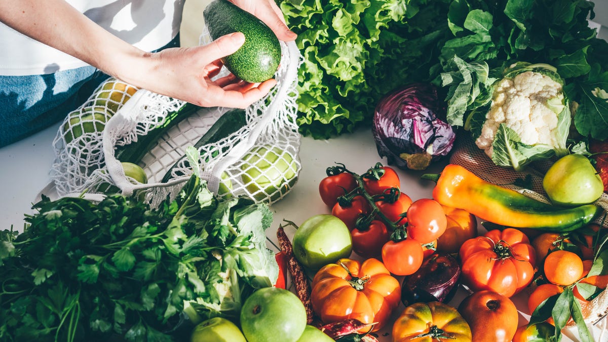 Woman takes fresh fruits and vegetables out from bag