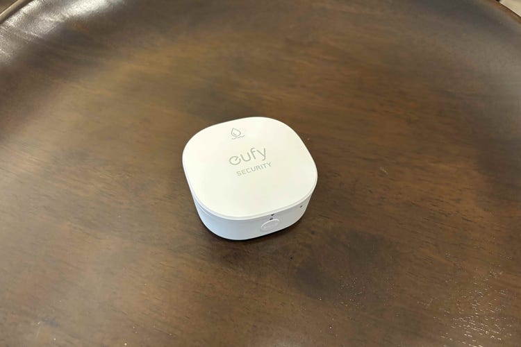 A white Eufy leak detector on a dark wood table. 