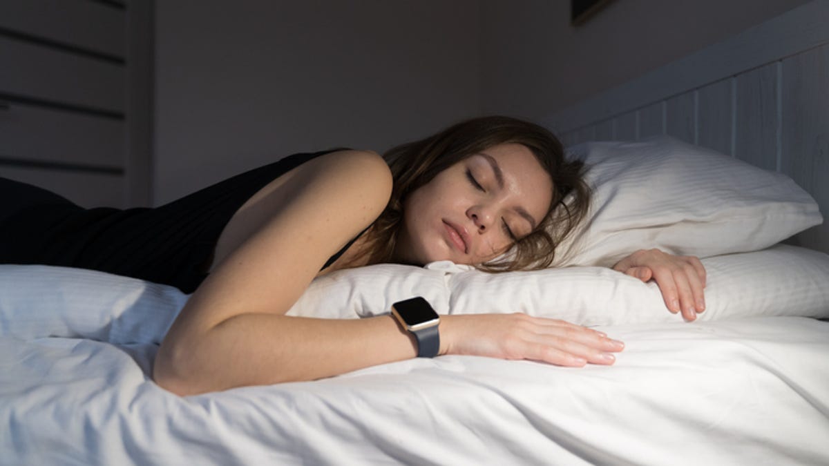 Woman sleeping on her side with a sleep tracker her wrist.