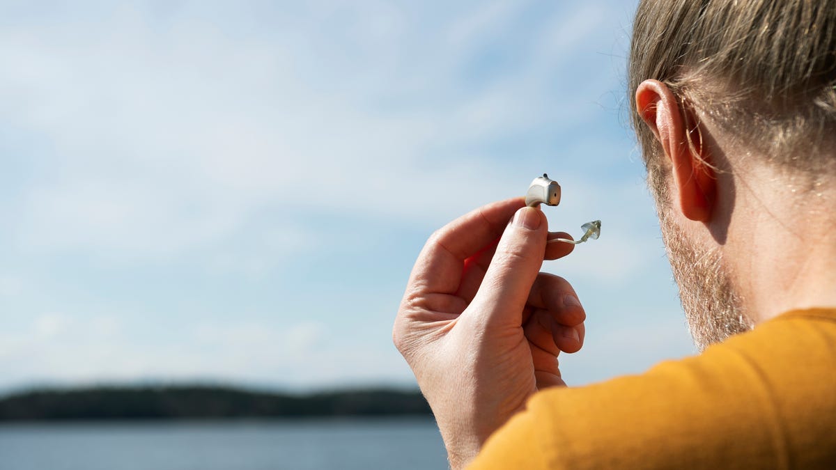 Man holding hearing aid outdoors