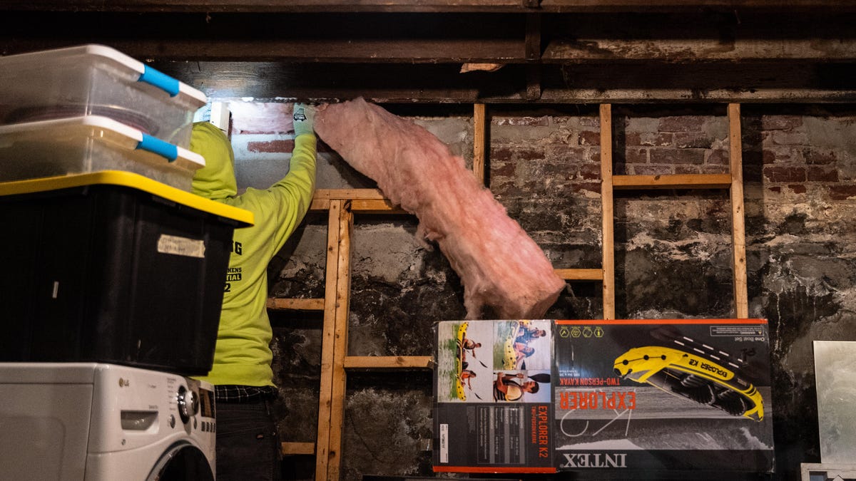 A worker installs insulation in a basement.
